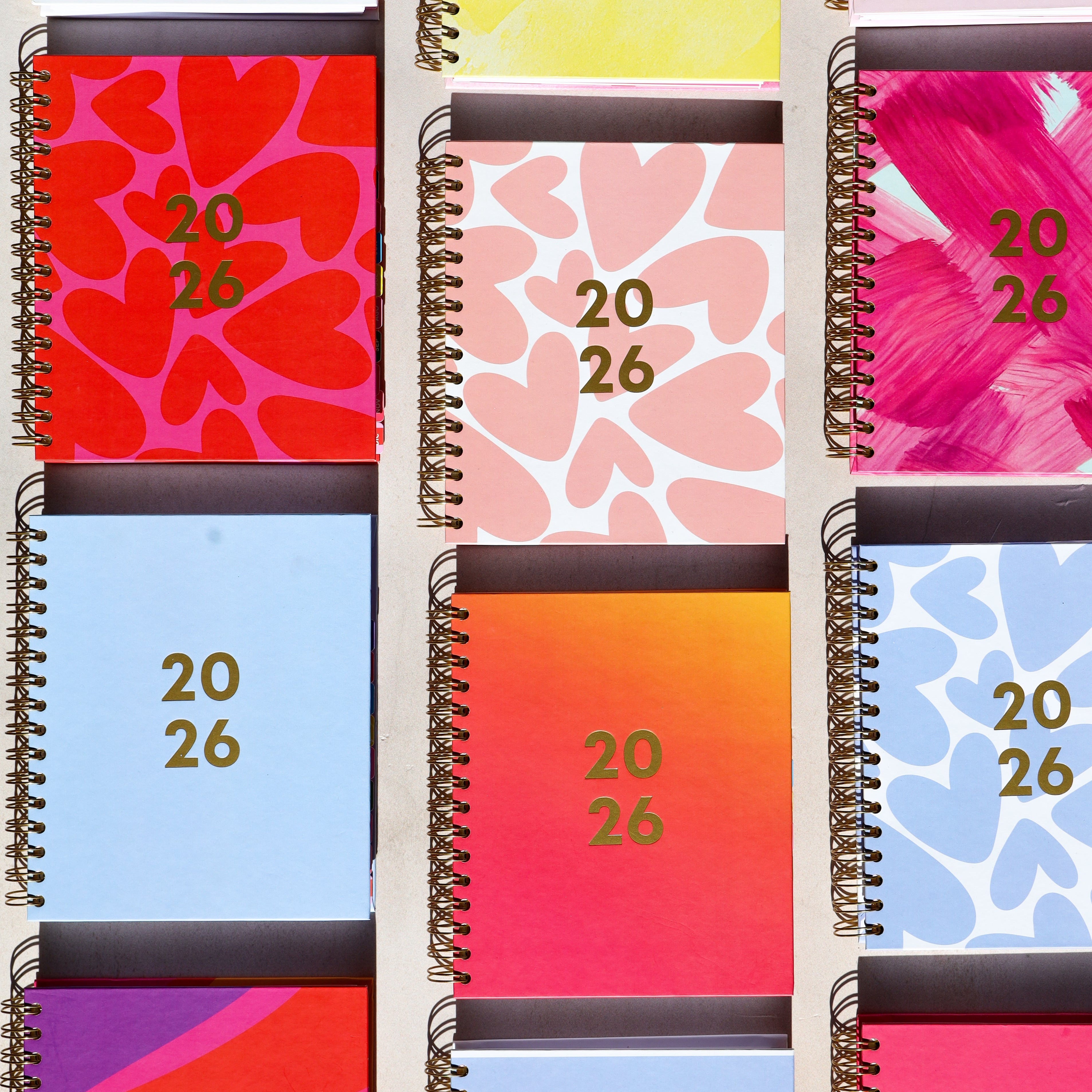 Set of colorful planners with spiral binding and patterned covers.